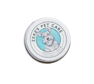 A metal tin with a label that reads "Zeke's Pet Care: Soothing pet balm: Veterinarian approved" The logo has a drawn image of a Schnauzer smiling.  Metal tin is .5oz